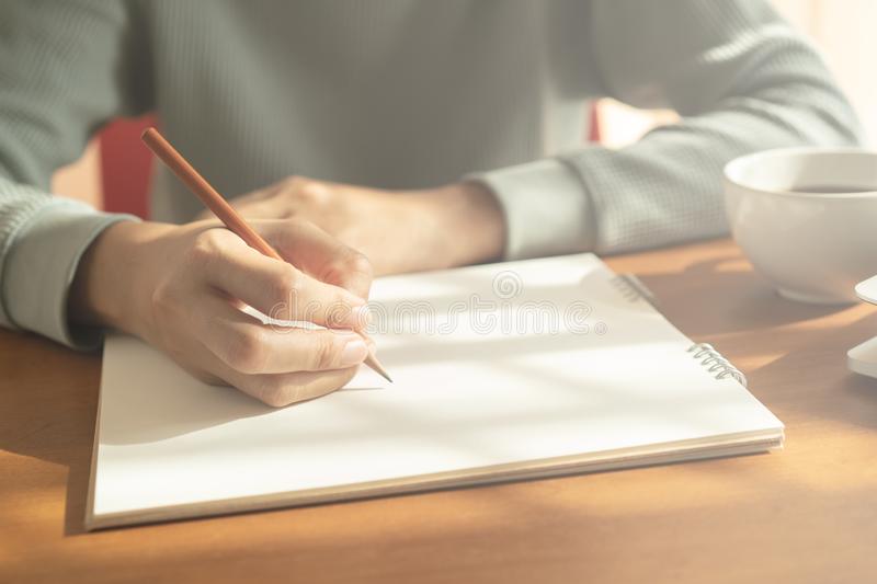 hands-woman-writing-notebook-wooden-desk-background-have-coffee-cup-laptop-morning-light-hands-woman-writing-notebook-146254250